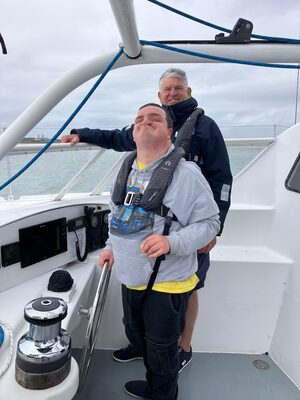 Young sailor at the helm of Spirit of Scott Bader, beaming with joy
